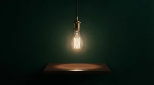 Leuchtende Glühlampe vor einem dunklen Hintergrund auf einem Holztisch
